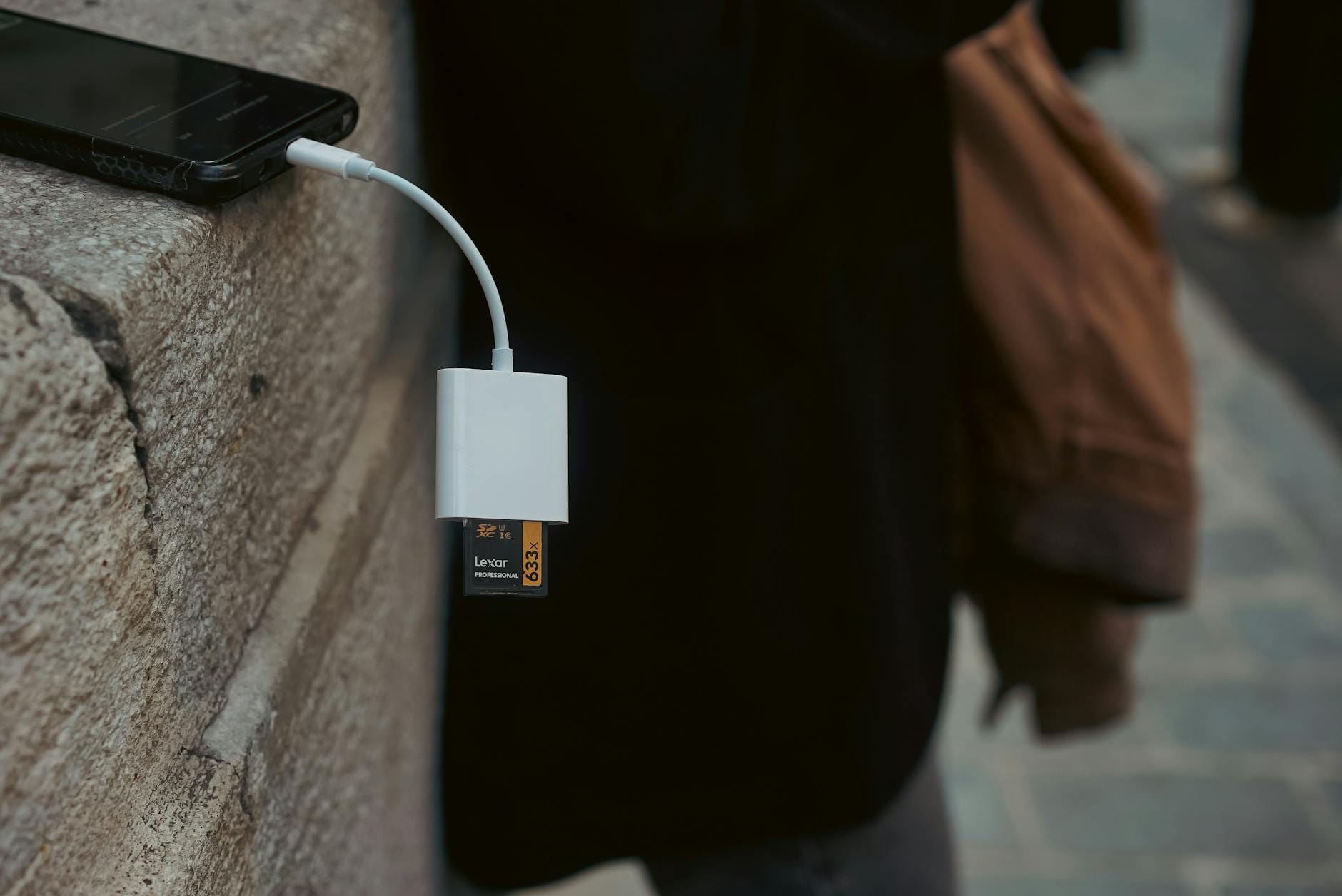 Smartfon na kamiennej powierzchni podłączony do czytnika kart pamięci