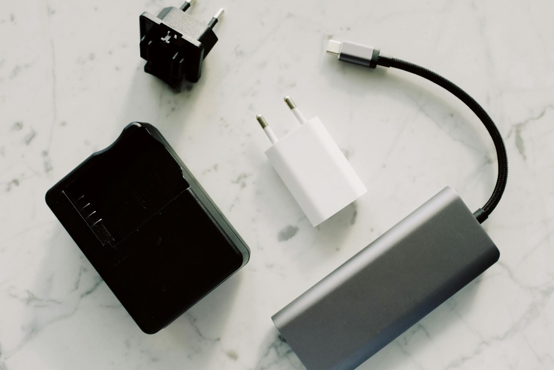 Adaptery i kable do ładowania smartfonów rozłożone na marmurowym blacie