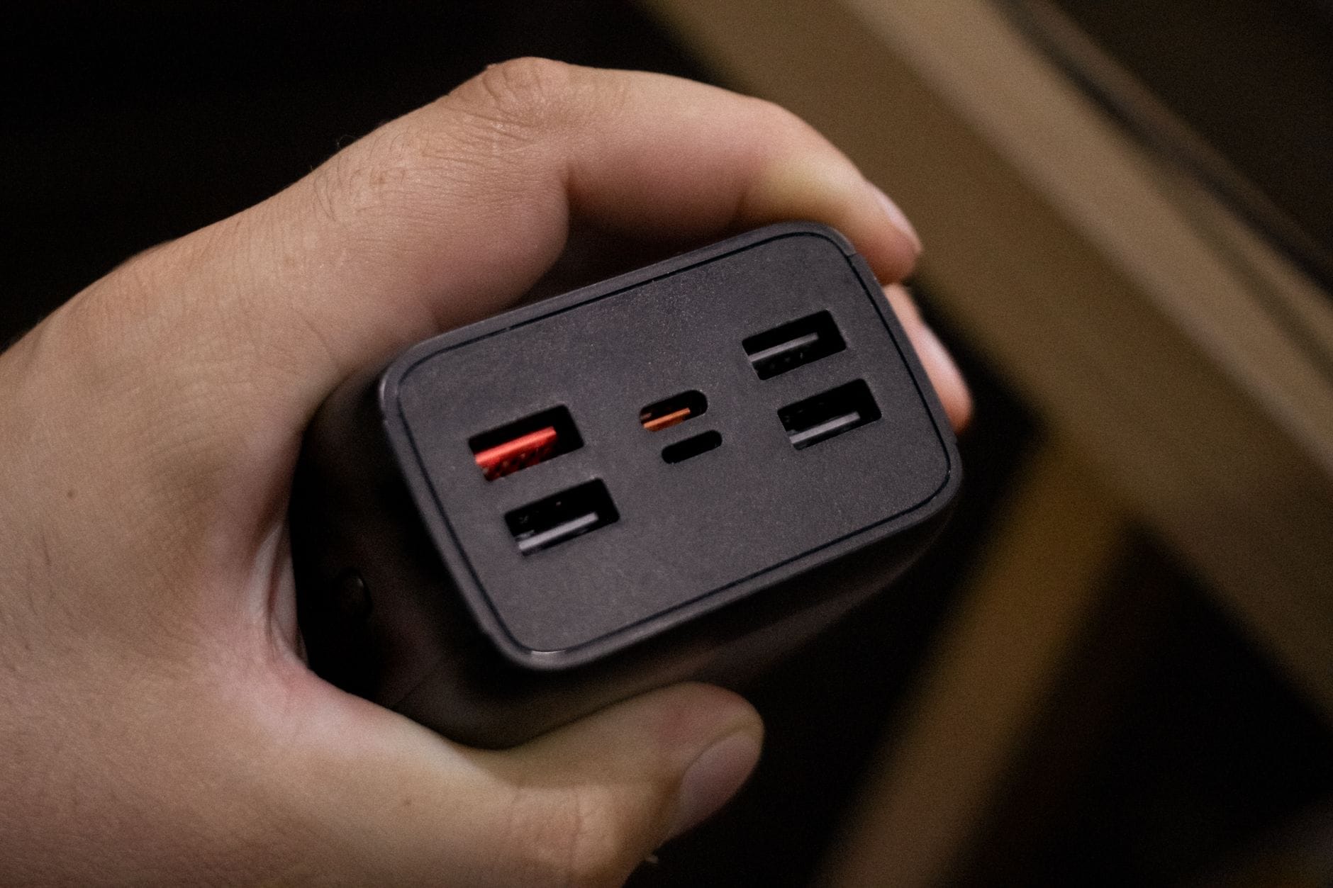 Dłoń trzymająca adapter z kilkoma portami USB do ładowania urządzeń