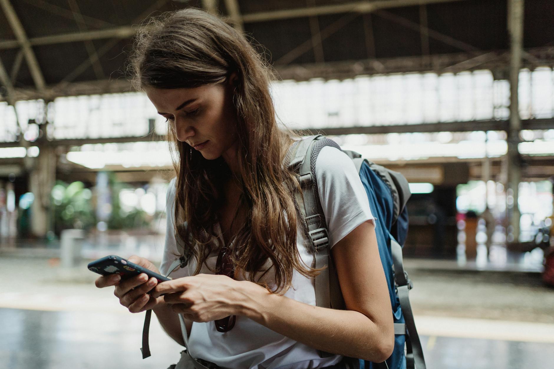 Kobieta na dworcu kolejowym sprawdza internet w telefonie