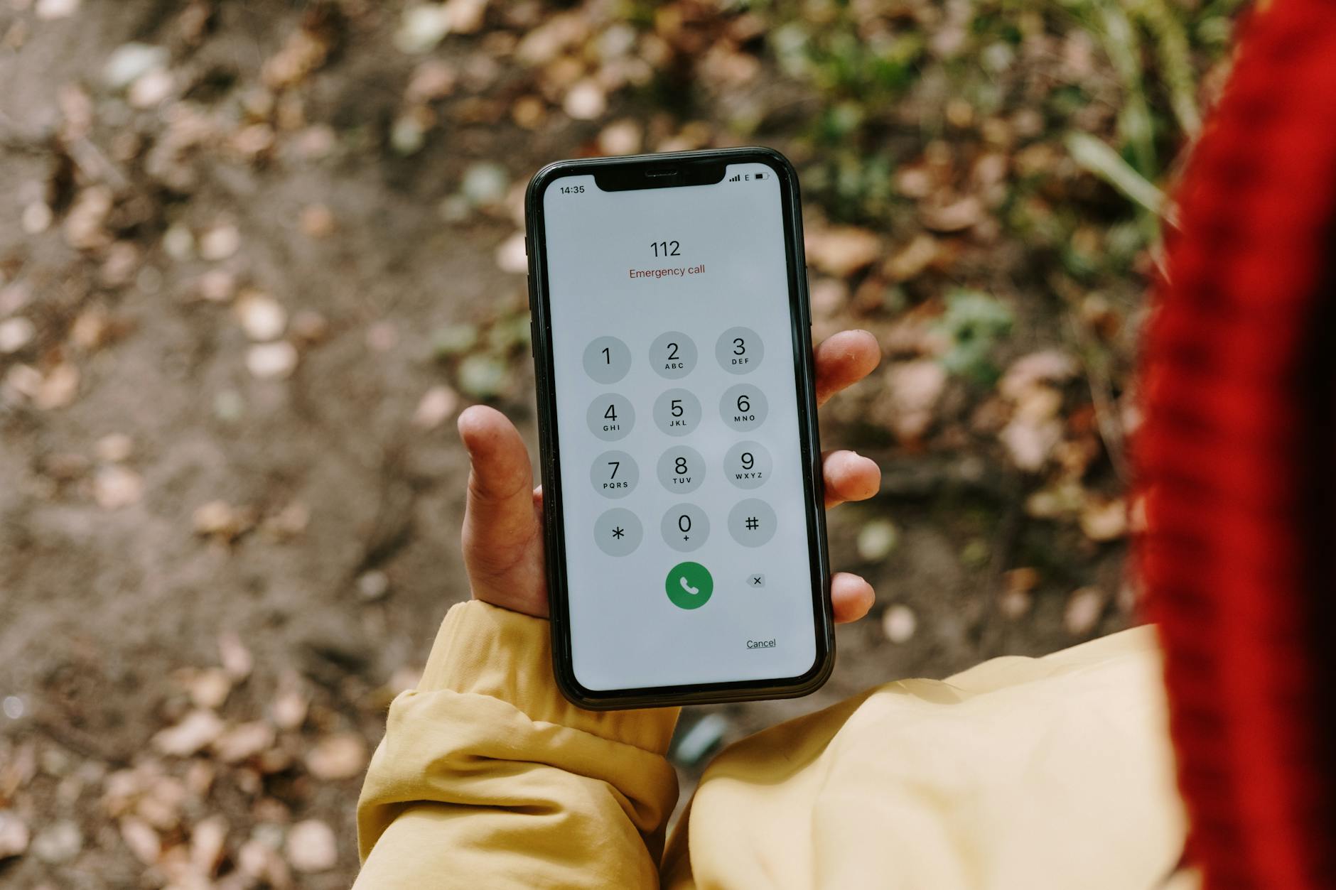 Smartfon na dworze z wyświetlonym numerem alarmowym 112