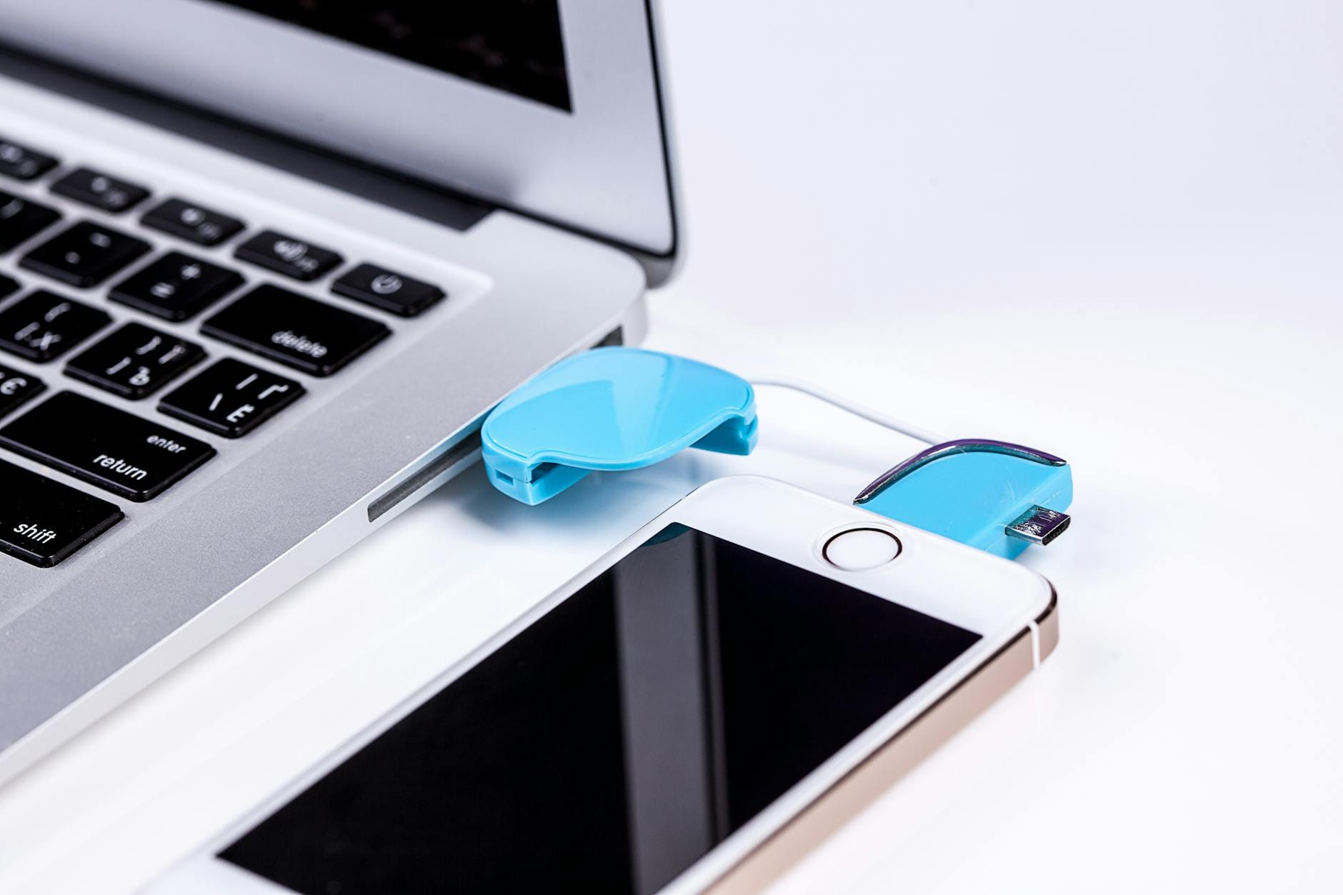Smartfon podłączony kablem USB do laptopa podczas przenoszenia danych