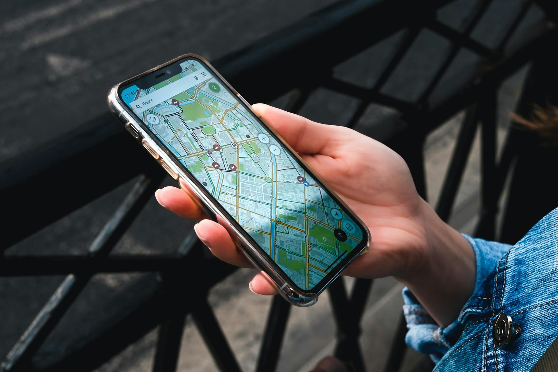 Dłoń trzymająca smartfon z otwartą mapą w aplikacji na zewnątrz