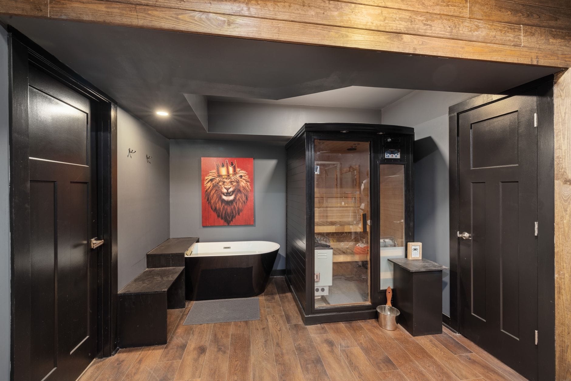 Domowa strefa spa z czarną sauną, wanną i obrazem lwa na ścianie