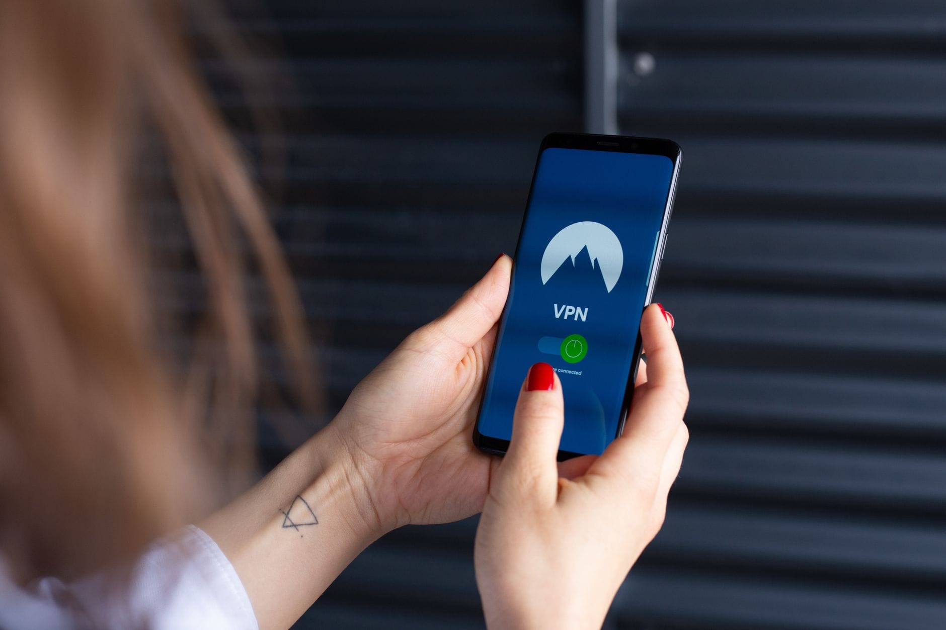 Czy darmowe VPN na telefon są bezpieczne i które warto zainstalować Kobieta trzyma smartfon z włączoną aplikacją VPN dla bezpieczeństwa telefonu