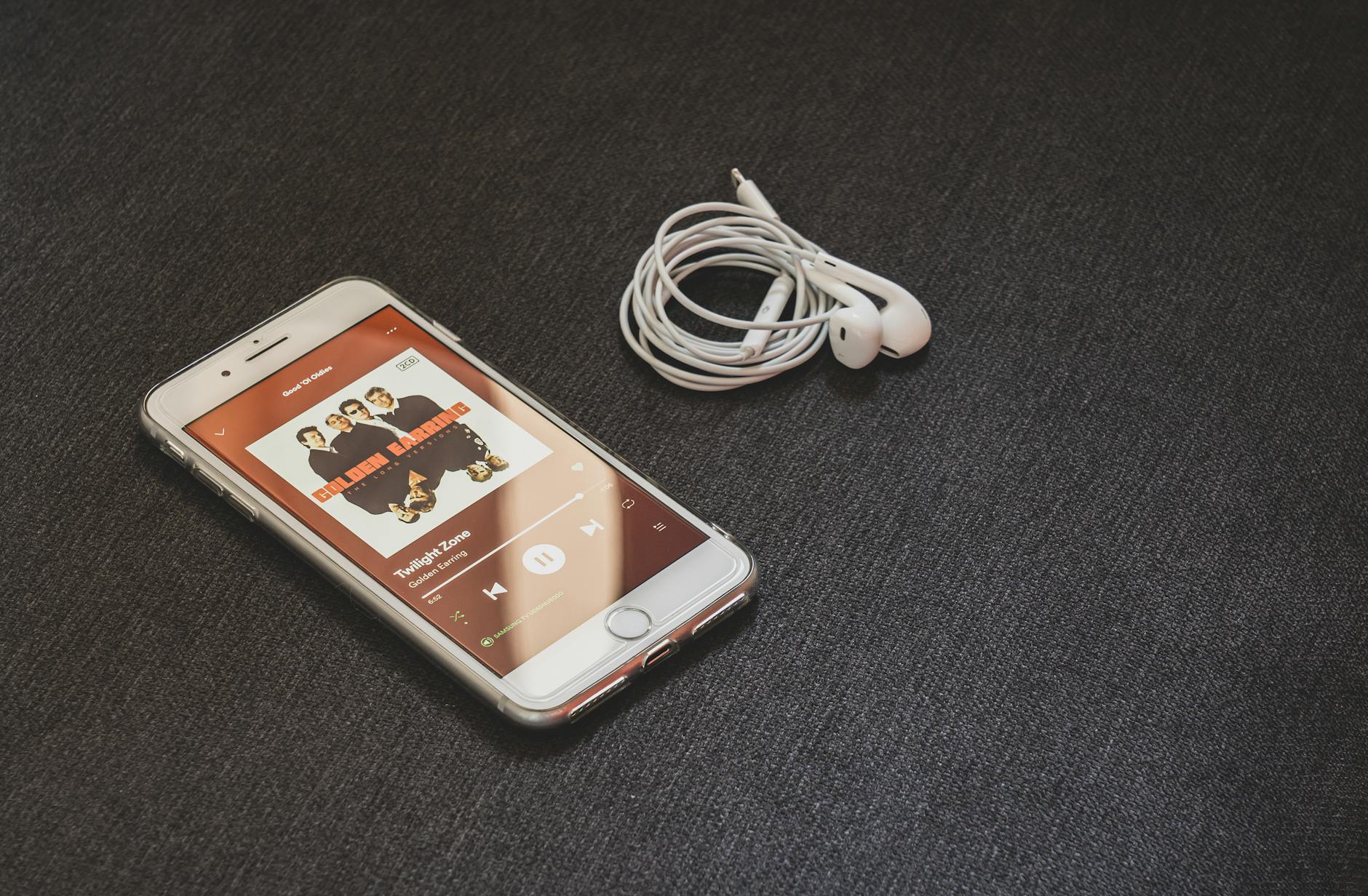 iOS nie widzi słuchawek Bluetooth albo rozłącza je sam z siebie – jak naprawić irytujące problemy z dźwiękiem Smartfon z bezprzewodowymi słuchawkami na ciemnym tle