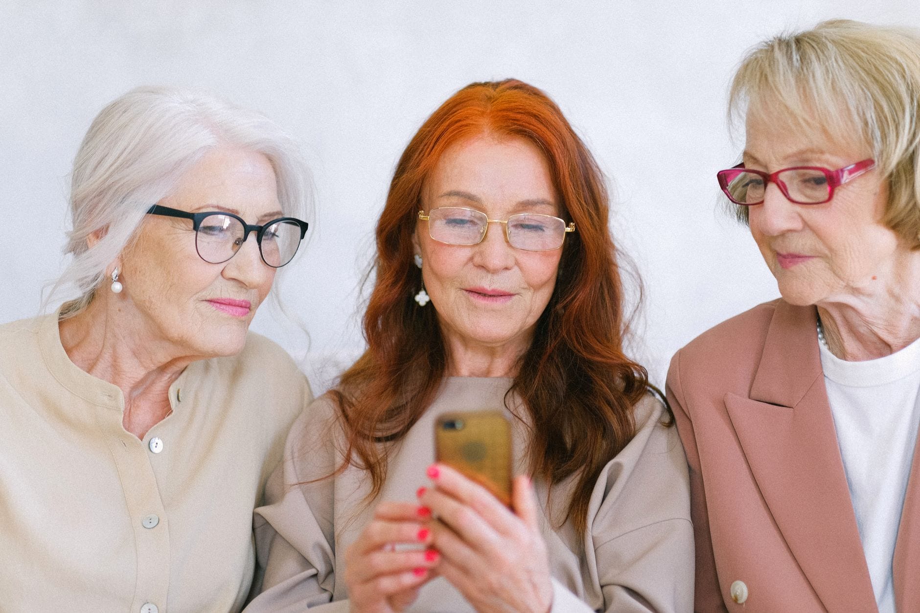 Eleganckie seniorki wspólnie przeglądają internet na telefonie