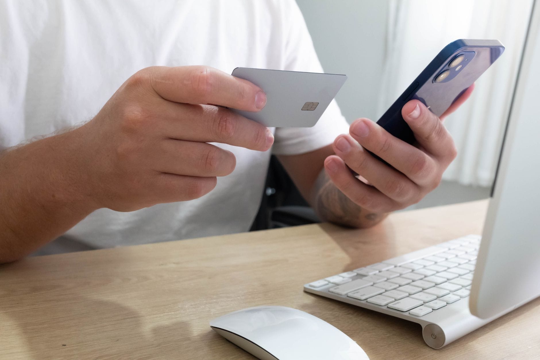 Osoba przy biurku trzymająca smartfon z Androidem i kartę płatniczą
