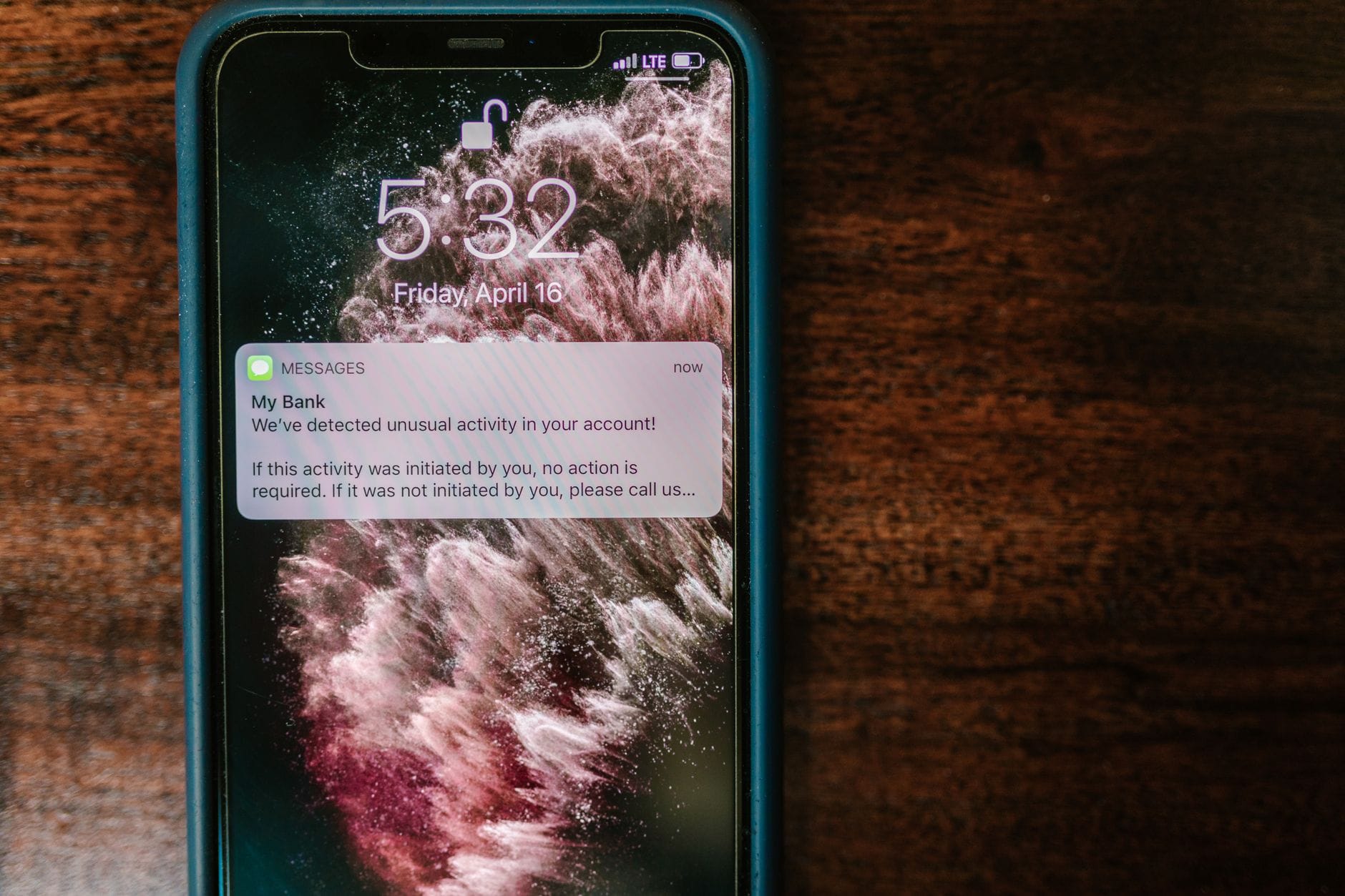 Smartfon z powiadomieniem z banku leżący na drewnianym stole