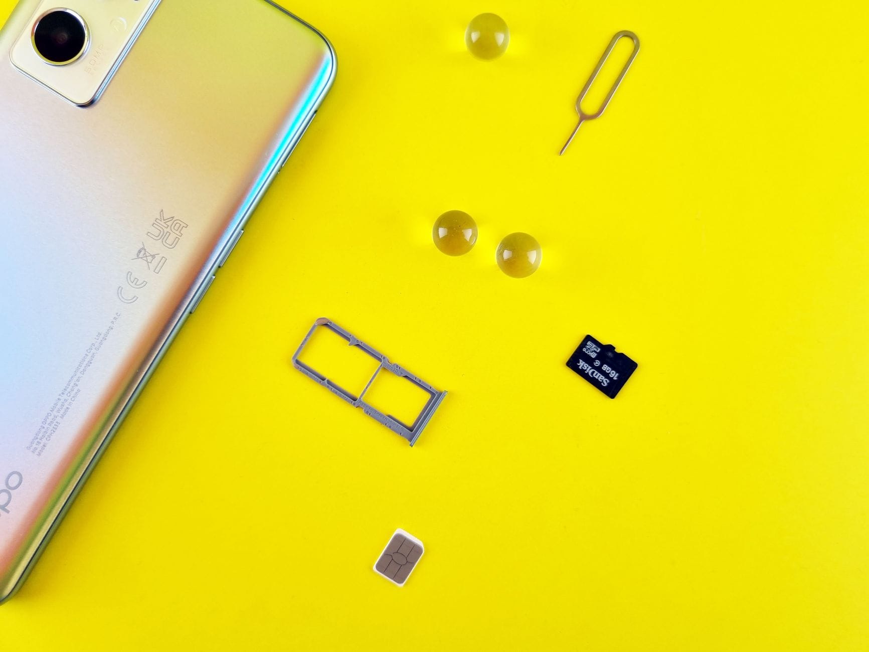 Smartfon z wysuniętą tacką SIM i kartą microSD na żółtym tle
