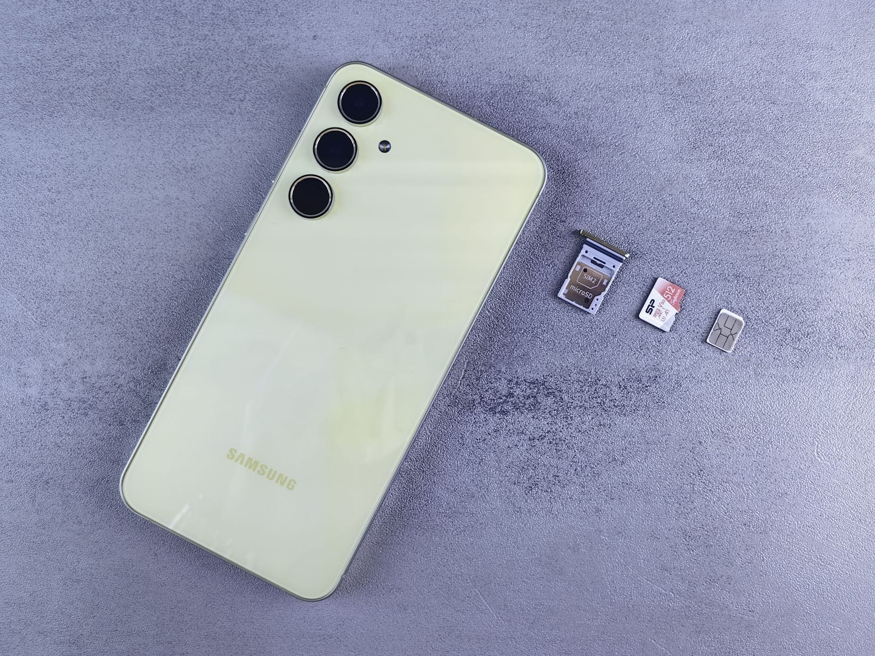 Żółty smartfon z tacką SIM, kartą pamięci i kartą SIM na szarym tle